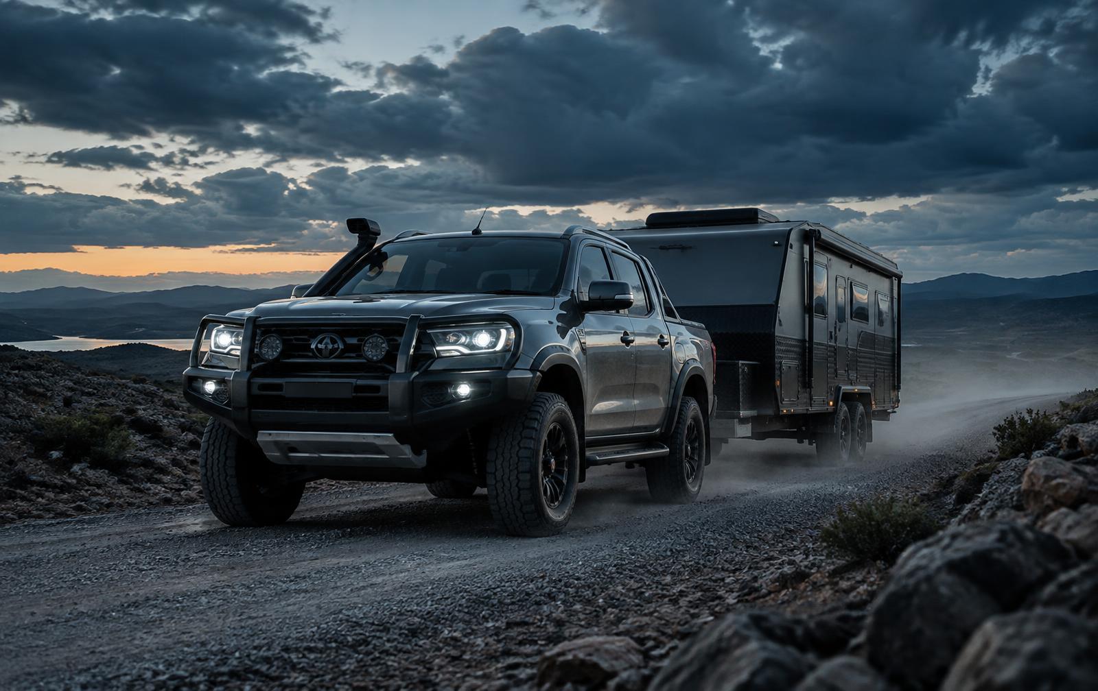 Dark dual-cab towing on a remote gravel road